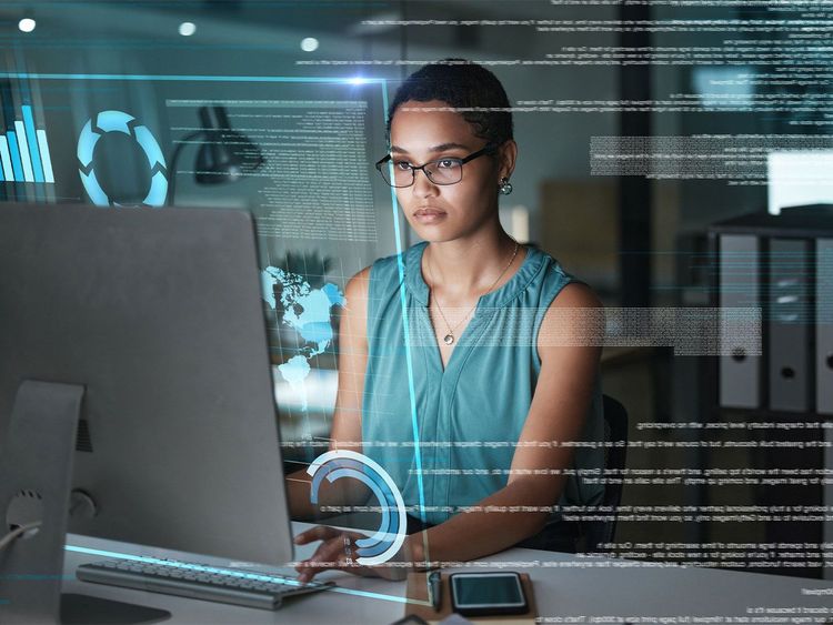 Frau mit Brille arbeitet konzentriert an einem Computer, umgeben von digitalen Daten und Grafiken