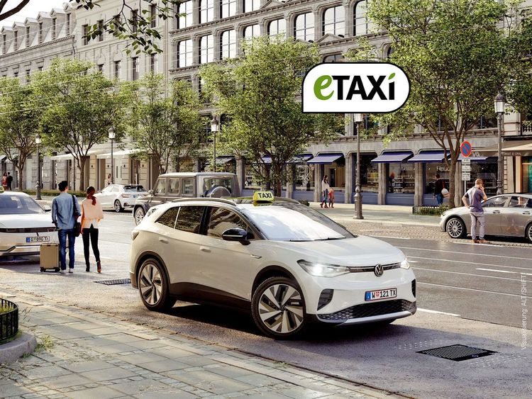 Weißer Volkswagen ID.4 als Elektro-Taxi steht an einer Straße in der Stadt, Passanten warten auf dem Bürgersteig, Gebäude und Bäume im Hintergrund