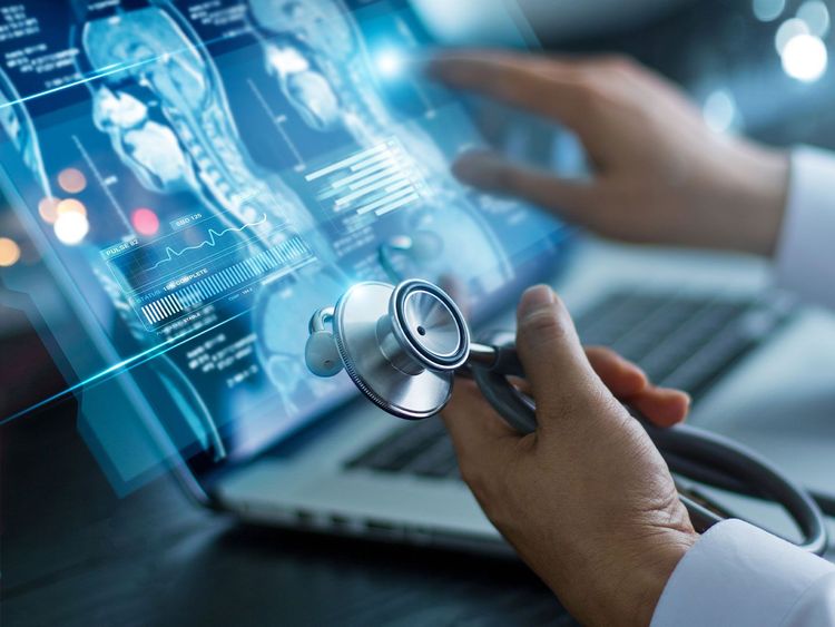 Arzt hält Stethoskop und interagiert mit digitalen medizinischen Bilddaten auf einem Laptop